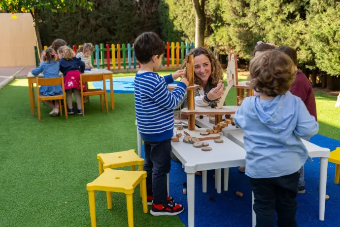 profesora infantil con niños mesa bancos amarillos